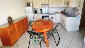 Una cocina compacta con mesa, sillas, microondas, lavadora y armarios.
