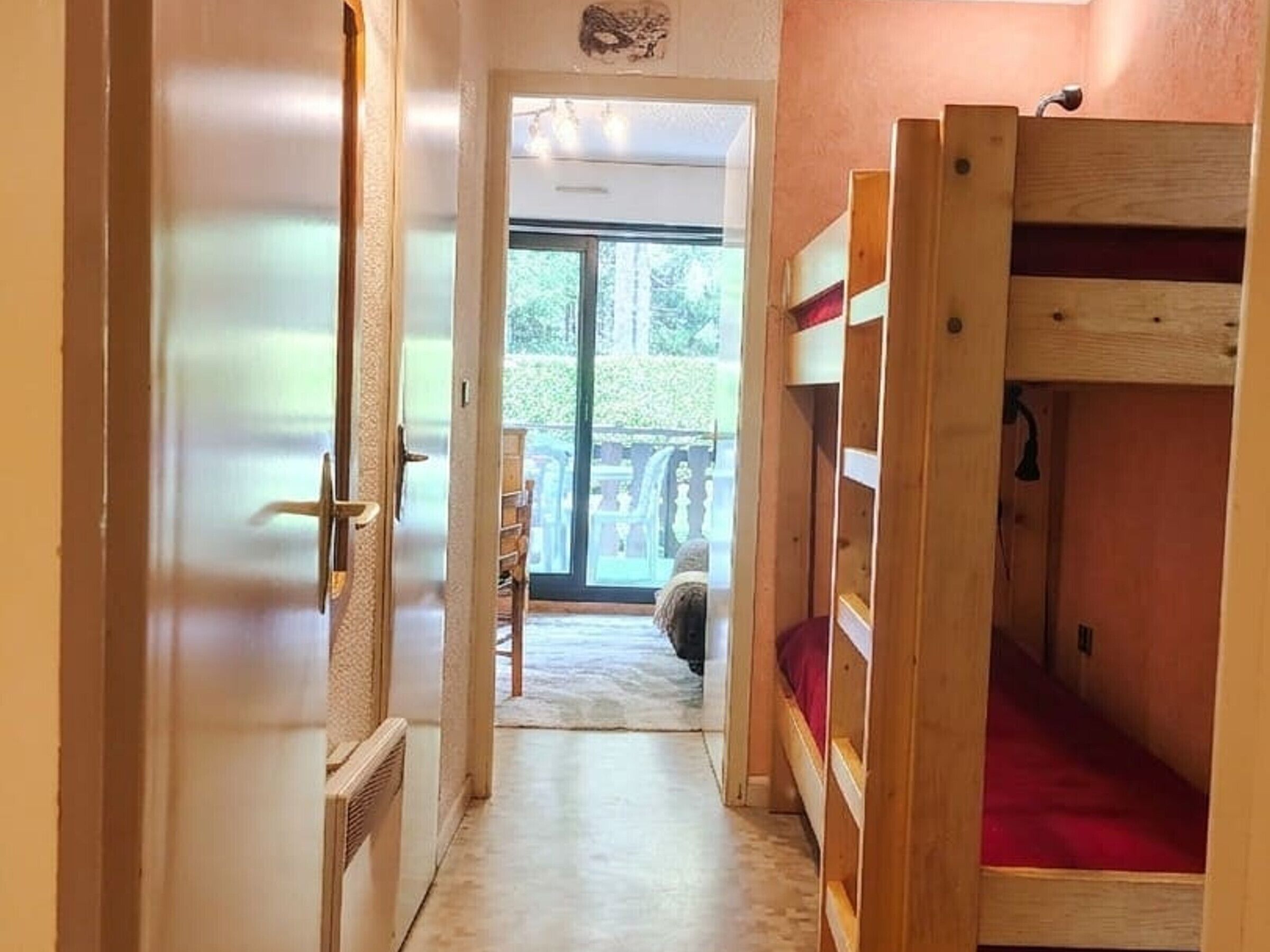 A room with bunk beds, a door leading to a balcony, and a view of the outdoors.
