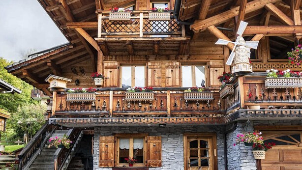 A wooden chalet with a stone facade, wooden balconies with lattice railings, and a windmill. - Studio with terrace, 4 pers, pets allowed, parking (Châtel)