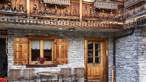 A stone building with wooden shutters, a balcony with intricate lattice work, and a table with chairs outside. - Studio with terrace, 4 pers, pets allowed, parking (Châtel)