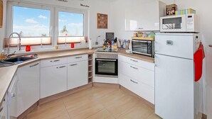Eine moderne Küche mit weißen Schränken, einem Backofen, einer Mikrowelle und einem Spülbecken.