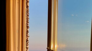 Ein Balkon mit Meerblick, einer Küstertopfpflanze und einer Schiebeglastür.