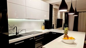 Eine moderne Küche mit weißer Arbeitsplatte, schwarzen Schränken und einer Stein-Spritzschutzwand.