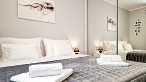 Ein Hotelzimmer mit einem großen Bett, zwei Nachttischen mit Lampen, einem Spiegel und Bildern an den Wänden.