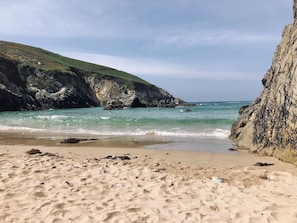 Ein sandiger Strand mit felsigen Klippen und ruhigem Meer.