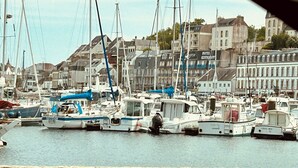 Uma marina com vários barcos atracados, rodeada por edifícios, incluindo um hotel e um restaurante.