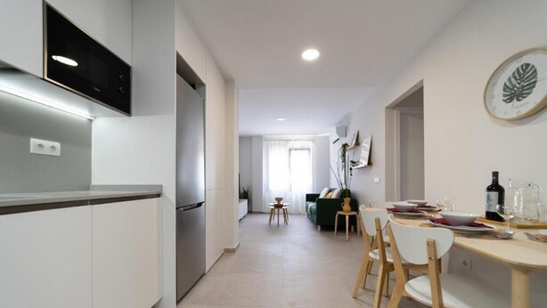 A modern kitchen with a built-in oven and a dining area with a table set for two.