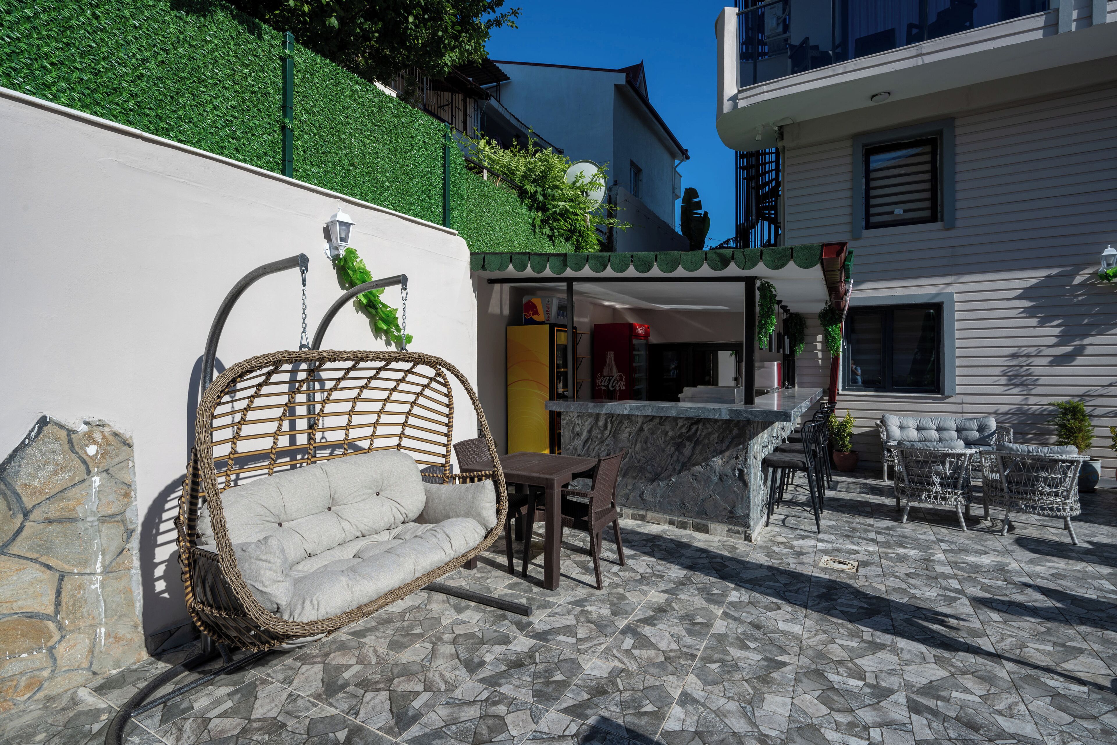 An outdoor patio with a wicker swing chair, a table, and chairs.