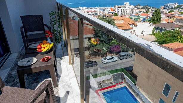 A balcony with a pool, a dining table with fruit, and a chair. - Otel Carpediem Gold Kuşadası (Kusadasi)