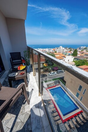 A balcony with a pool, a dining table with fruit, and a chair.