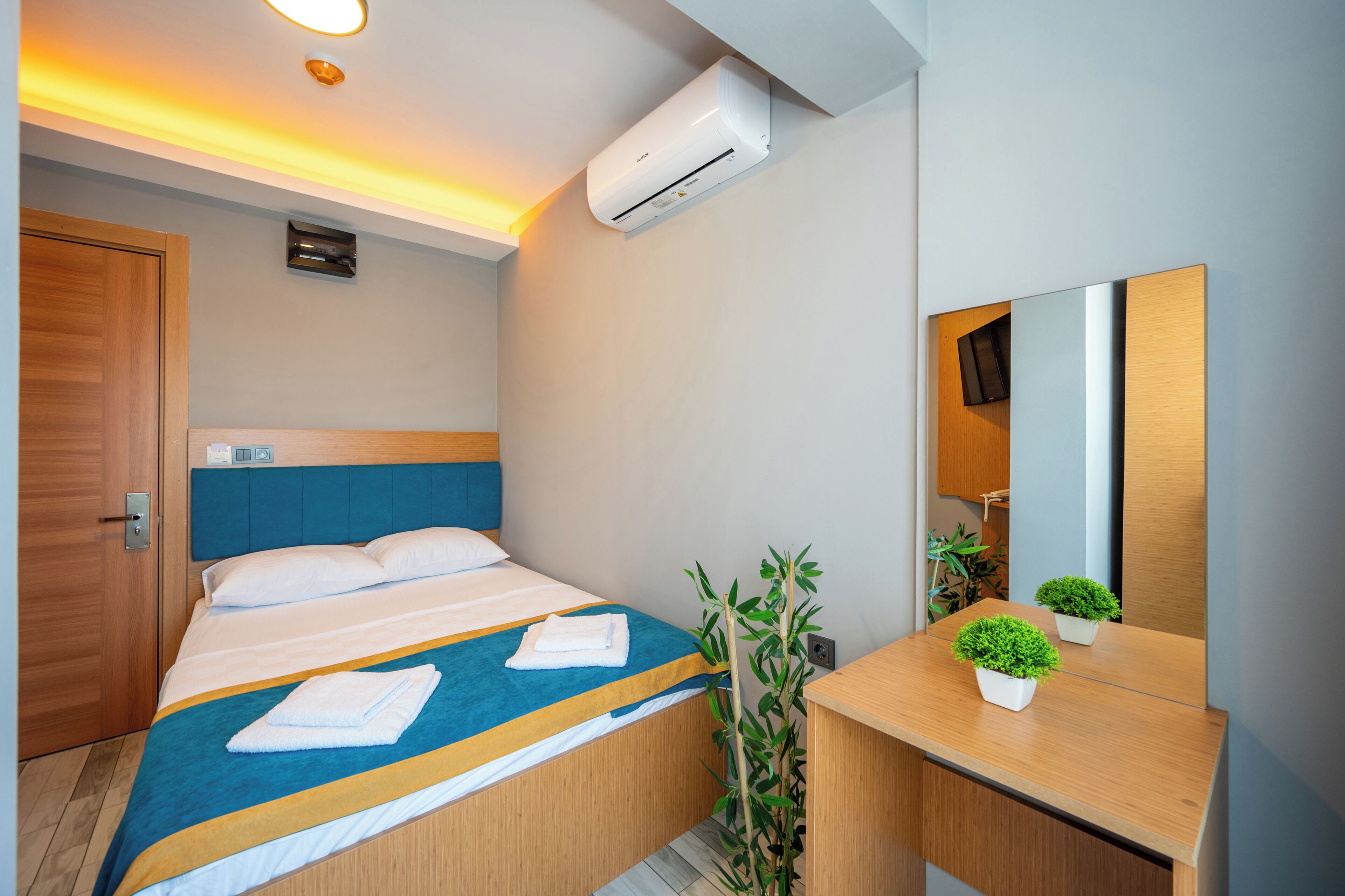 Una habitación de hotel moderna con cama, mesita de noche, espejo y aire acondicionado.