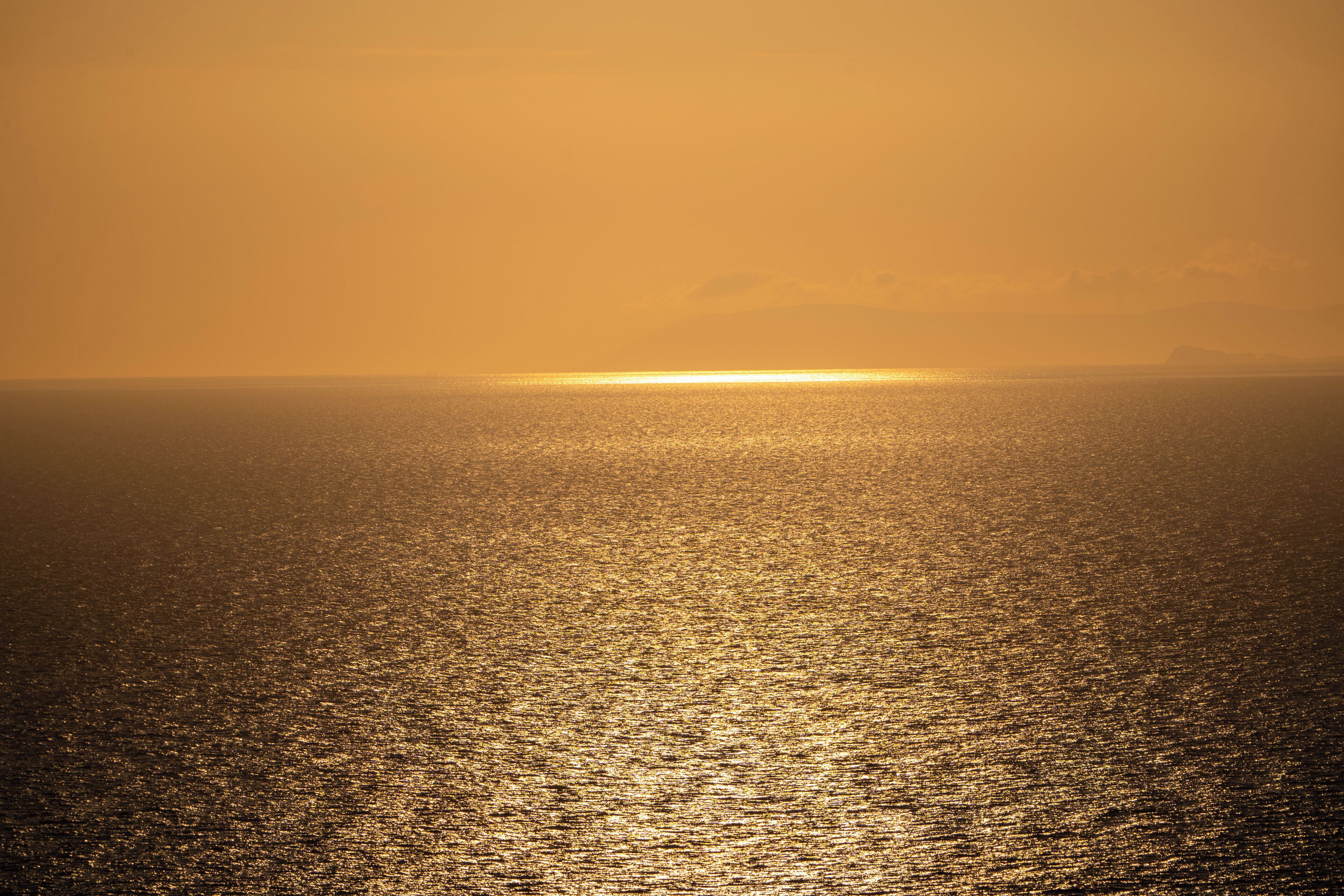 A sunset over a calm sea with a clear horizon.