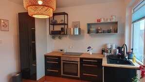 A modern kitchen with a wooden countertop, built-in oven, and a hanging light fixture.
