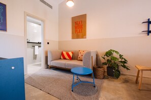 A modern living room with a sofa, a blue coffee table, a potted plant, and a wooden bench. - Gandum Village - Conscious Boutique Hotel (Montemor-o-Novo)