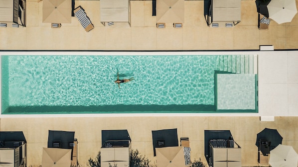 An aerial view of a swimming pool with lounge chairs and umbrellas. - Gandum Village - Conscious Boutique Hotel (Montemor-o-Novo)