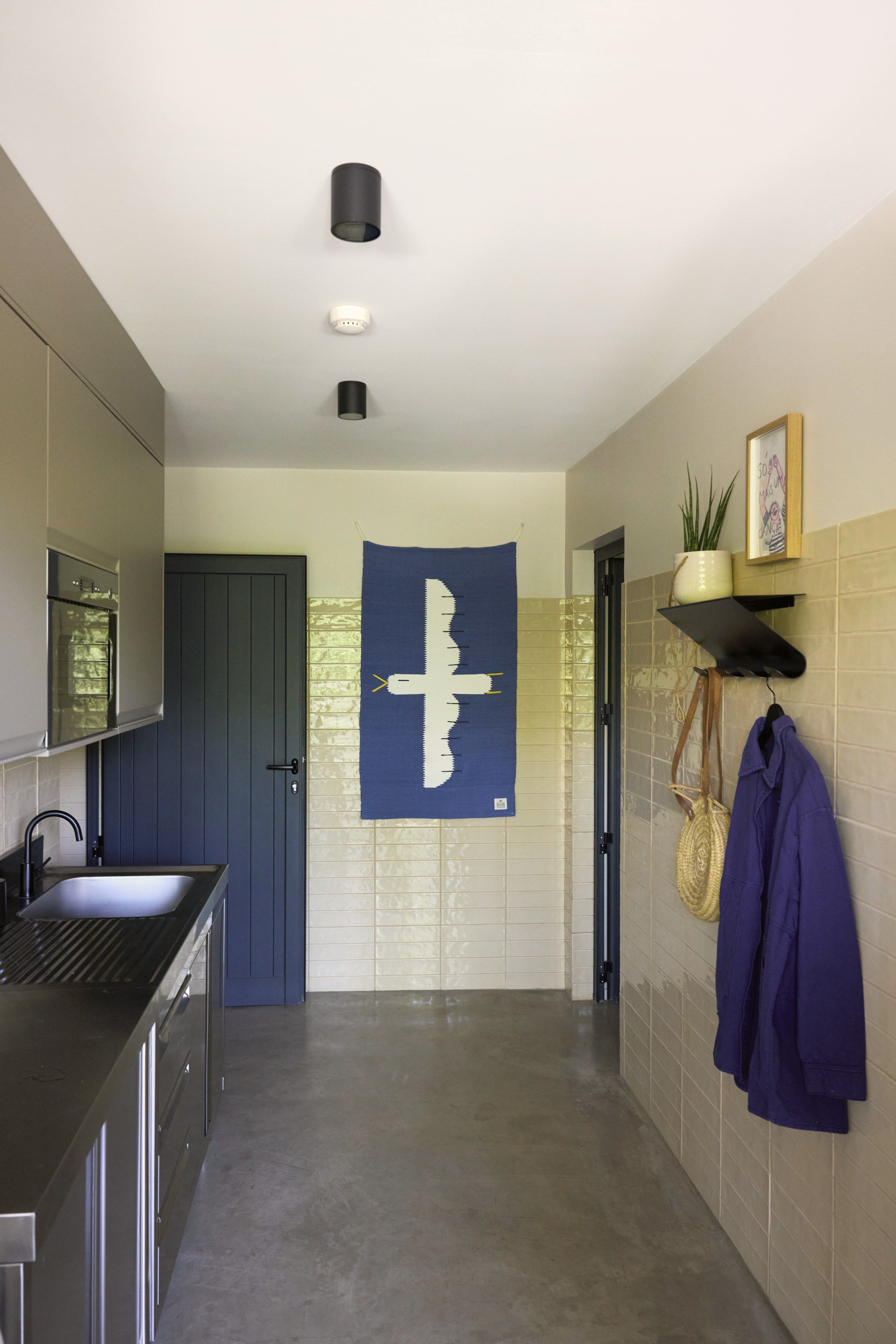 Een moderne keuken met een donkerblauwe deur, een gootsteen en een blauwe wandversiering.