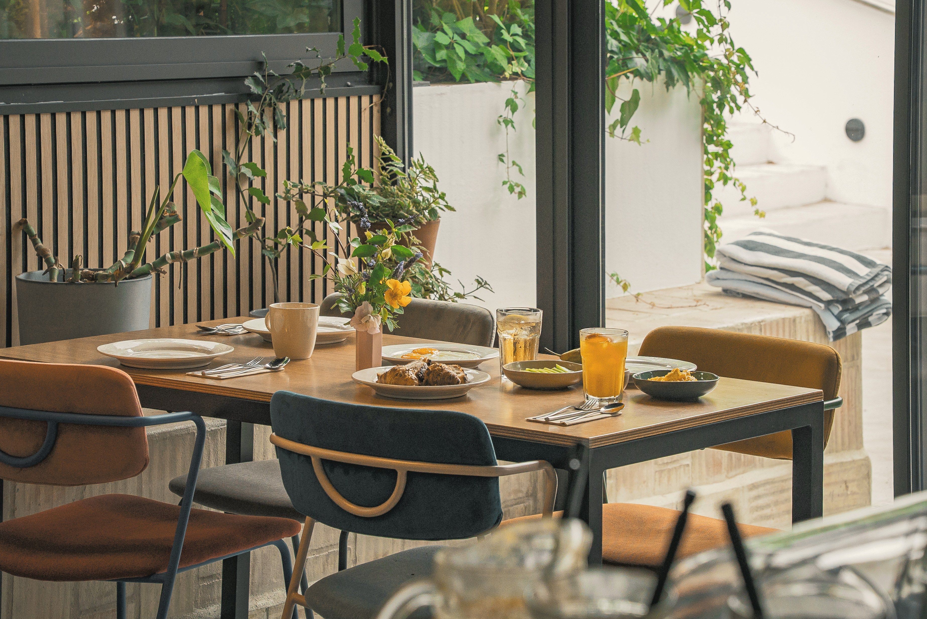 A dining table set with plates, cutlery, and glasses, surrounded by chairs.