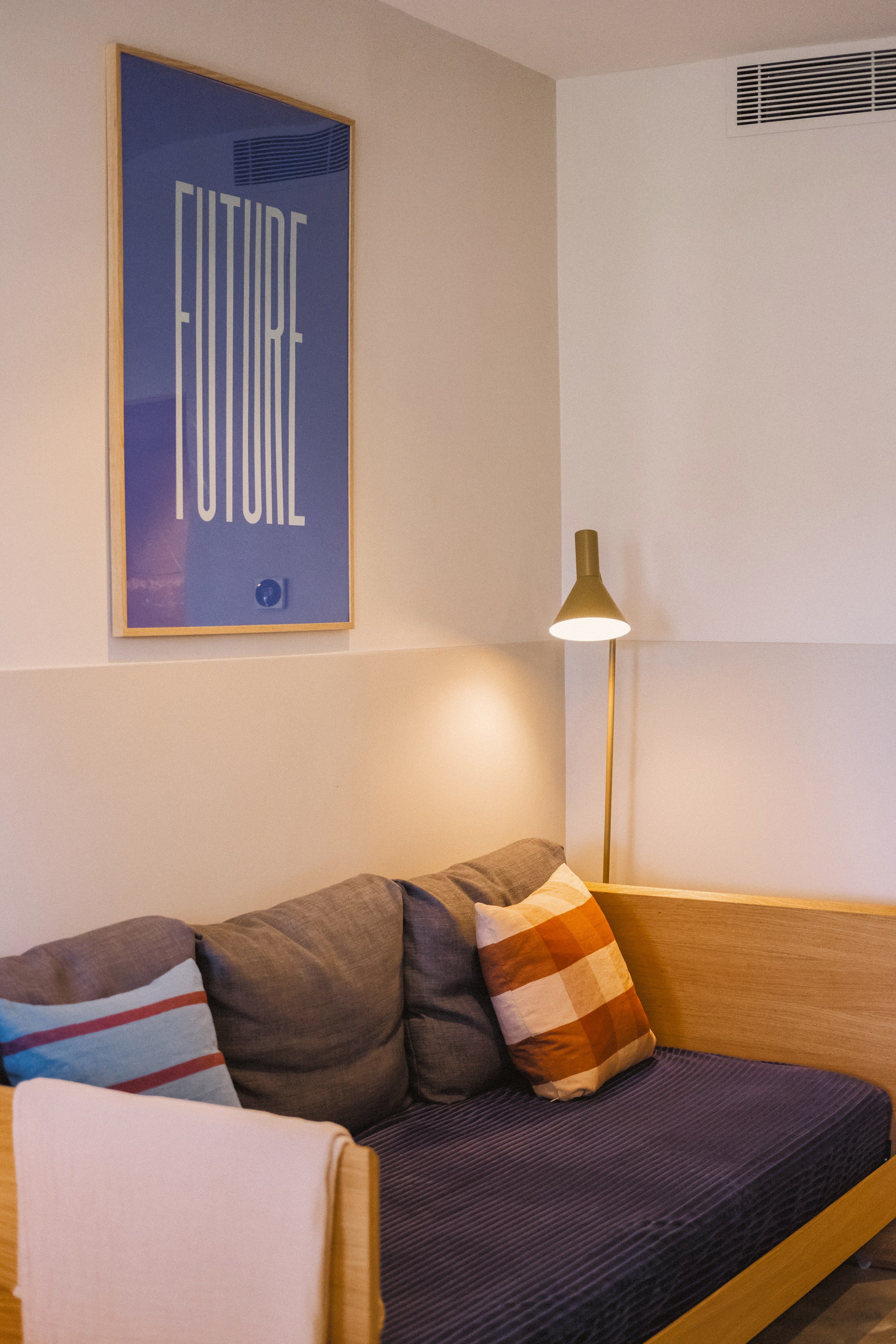 Una sala de estar moderna con sofá, almohadas, una lámpara de pie y un cartel en la pared.