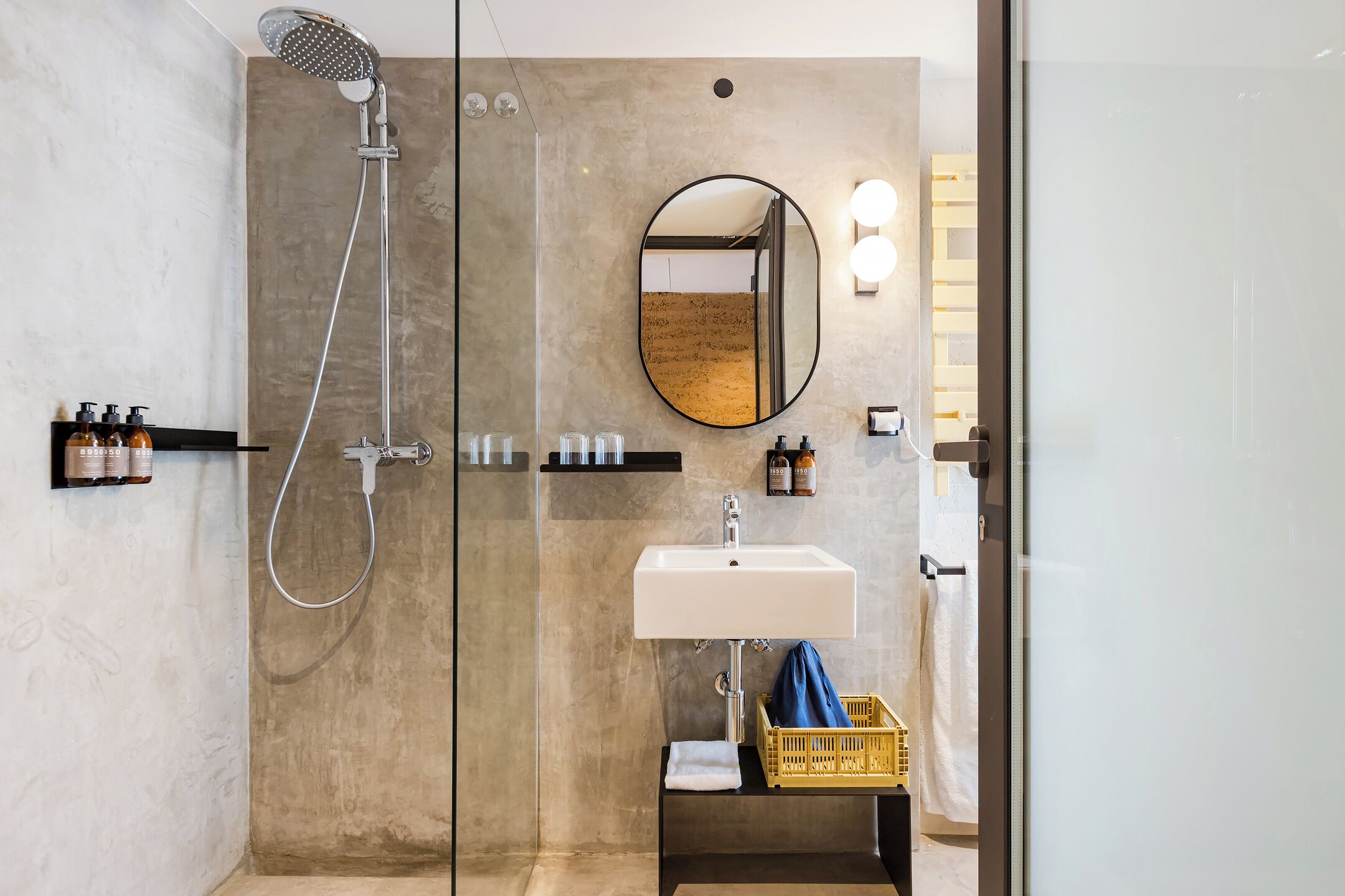 A modern bathroom with a glass-enclosed shower, a white sink, and a mirror with lights.