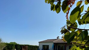 A swimming pool with a wooden deck, surrounded by a grassy area and a house with a tiled roof. - Spacious villa Le Charme with heated pool, 4 bedrooms sleeping 9, Airco & WiFi (Chalais)