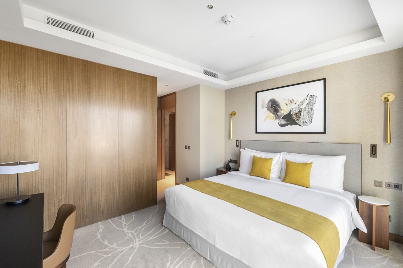 A hotel room with a large bed, a desk, and a chair.