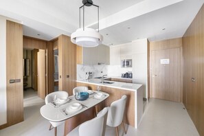 A modern kitchen with a central island, white cabinetry, and a built-in microwave. - StoneTree - Luxury 1BR - Prime Location (Dubai)