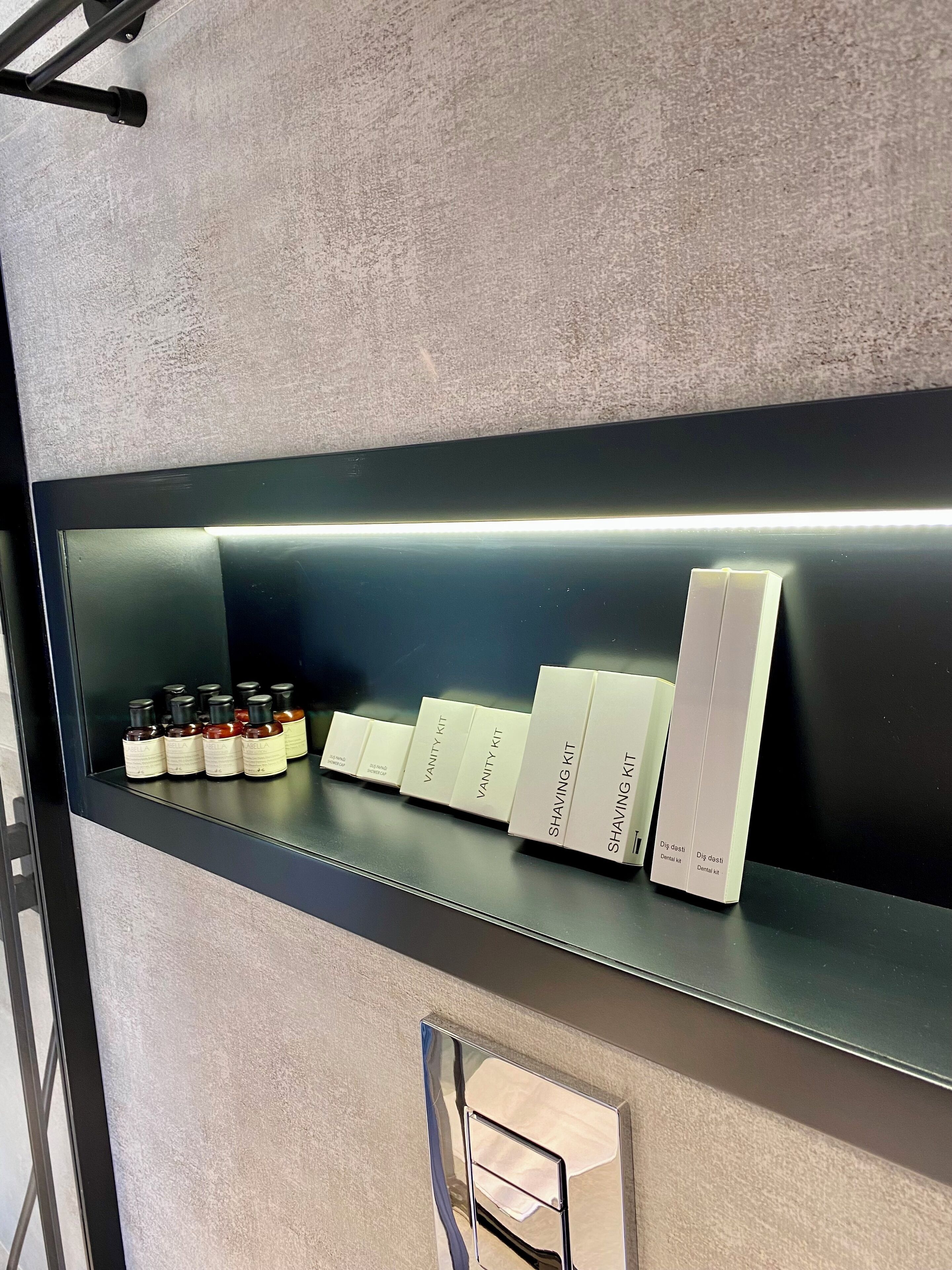 Ein Regal mit verschiedenen Hautpflegeprodukten, darunter Flaschen und Kartons mit den Aufschriften 'Vanity Kit' und 'Shaving Kit'.