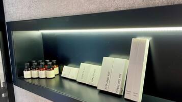 Ein Regal mit verschiedenen Hautpflegeprodukten, darunter Flaschen und Kartons mit den Aufschriften 'Vanity Kit' und 'Shaving Kit'.