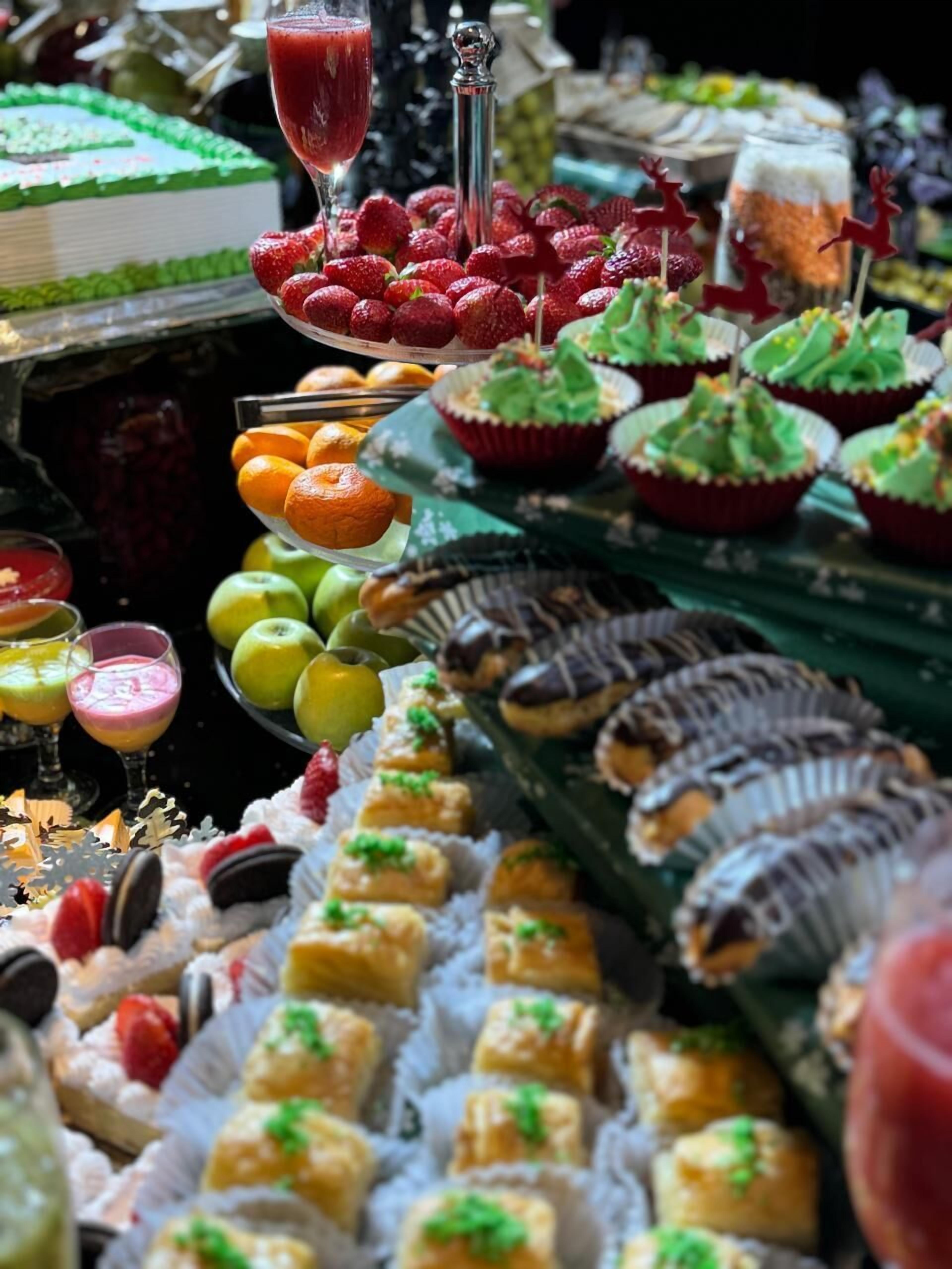 En buffet med et udvalg af mad, blandt andet frugt, kager og drikkevarer.