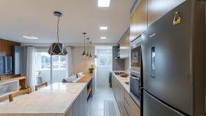 Una cocina moderna con una isla grande, electrodomésticos de acero inoxidable e iluminación colgante.