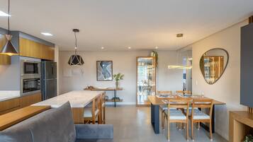 Una cocina moderna con electrodomésticos integrados, una zona de comedor con mobiliario de madera y un espejo grande en la pared.