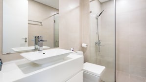 A modern bathroom with a large mirror, a white sink, and a glass-enclosed shower. - Hapi Riverside Apartment (Ho Chi Minh City)