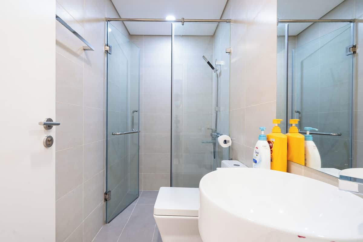 A modern bathroom with a glass-enclosed shower, a white toilet, and a large sink with toiletries.
