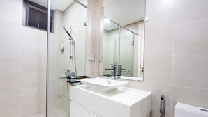 A modern bathroom with a glass shower enclosure, a white sink, and a large mirror. - Hapi Riverside Apartment (Ho Chi Minh City)