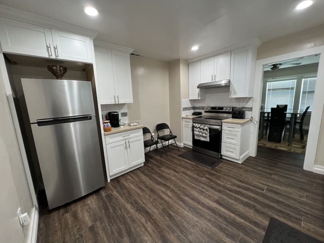 A modern kitchen with white cabinets, a stainless steel refrigerator, a built-in oven, and a microwave.