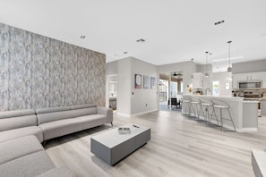 Un salon moderne comprenant un canapé, une table basse et un coin cuisine avec un bar et des sièges.