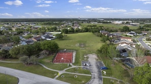 An aerial view of a residential area with houses, a basketball court, and a road. - 5390 Vacation Sunset House Private Pool Grill (Kissimmee)