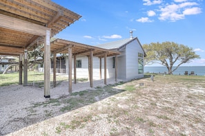 A covered outdoor area with a building adjacent to a body of water. - The Cape House 6031rpf 2 Bedroom Home by RedAwning (Rockport)