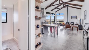 A spacious kitchen with high ceilings and exposed beams, a central island, and a view of the outdoors. - The Cape House 6031rpf 2 Bedroom Home by RedAwning (Rockport)