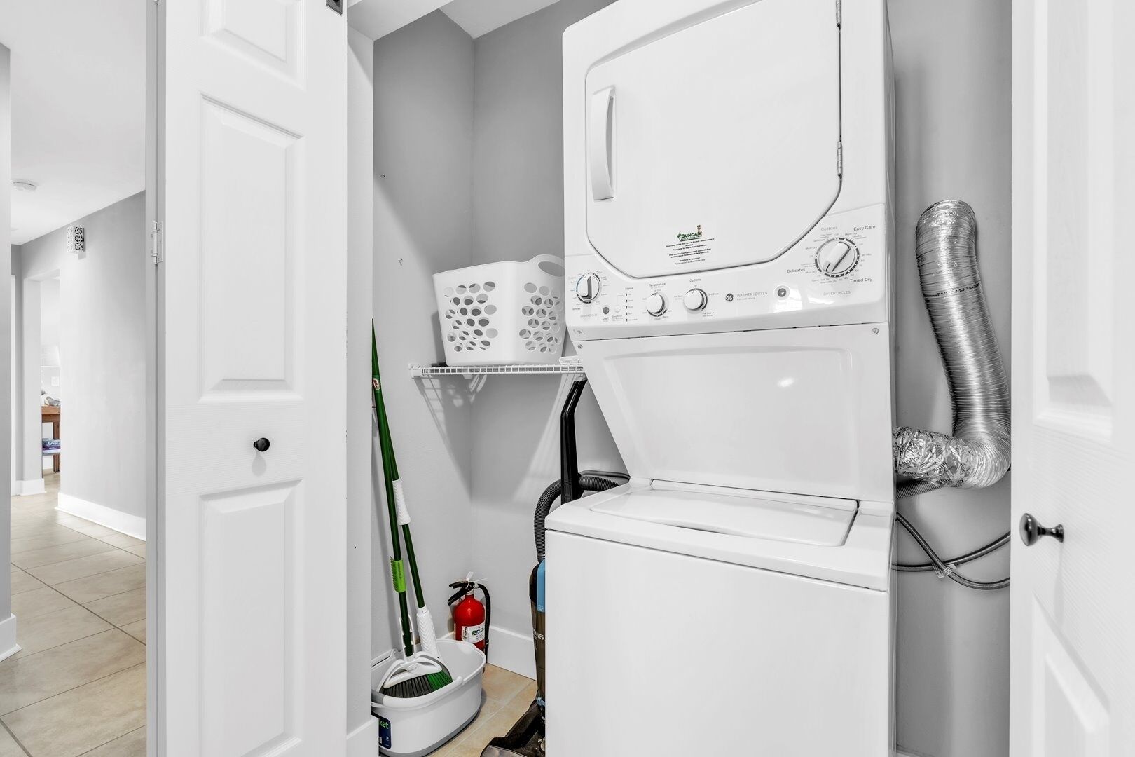 A laundry room with a front-loading washing machine, a dryer, and a vent hose.