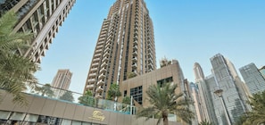 A high-rise building with a modern architectural design, featuring multiple balconies and a prominent glass facade.
