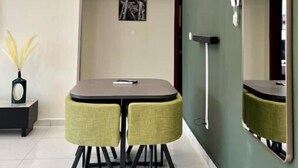 Un comedor moderno con una mesa y sillas, un espejo montado en la pared y una obra de arte enmarco.