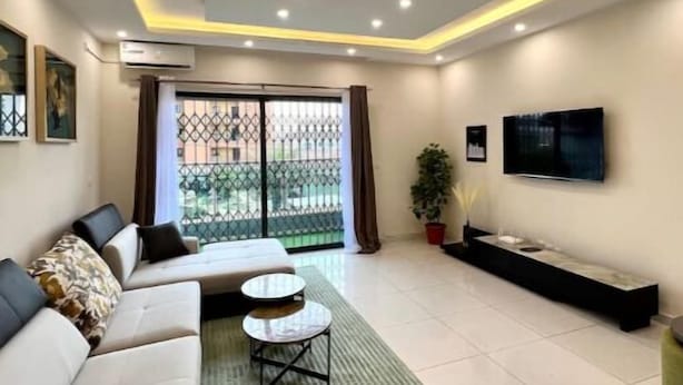Una sala de estar moderna con un sofá, una mesa de centro, un televisor y un balcón con vistas.