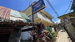 A street view with a building featuring a sign for "Pepe's Mindure Empanada". - Peters Inn Puerto Galera (Puerto Galera)