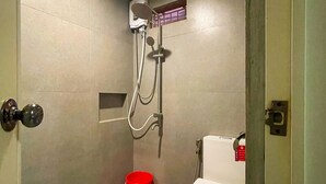 A small, modern bathroom with a shower, toilet, and a red bucket. - Peters Inn Puerto Galera (Puerto Galera)