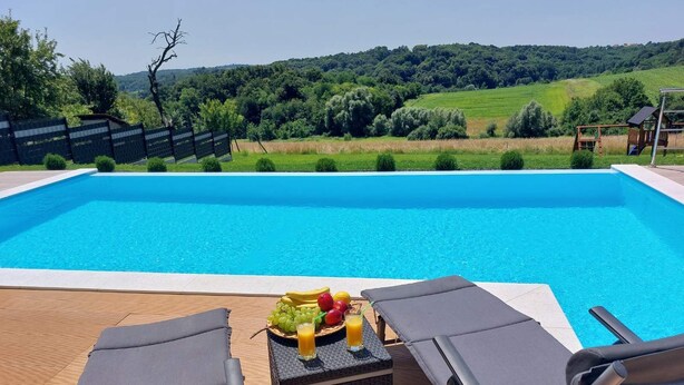 Une piscine avec des chaises longues et une table où sont disposés des fruits et des boissons.