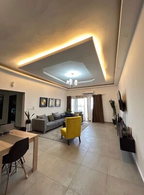 Relax and socialize in this inviting living space with a dining area, comfortable seating, and a large window offering a view of the outdoors.
