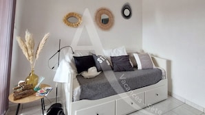 A neatly arranged bedroom with a bed, bedside table, lamp, and decorative mirrors. - Studio avec terrasse et parking, proche plages (Sète)