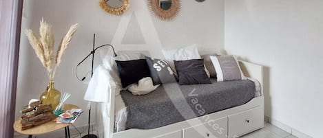 Une chambre à coucher bien rangée, avec un lit, une table de chevet, une lampe et des miroirs décoratifs.