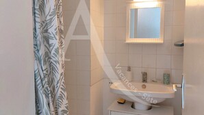 A bathroom with a white sink, mirror, and tiled walls. - T3 avec balcon coeur quartier Corniche (Sète)